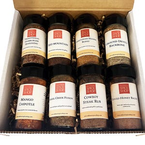 Pu&ograve; includere: Una scatola regalo piena di otto piccoli barattoli di vetro di spezie. I barattoli sono etichettati con i nomi delle spezie, tra cui "Condimento tradizionale per hamburger", "Red Mountain", "Miscela di prateria Switchgrass", "Spina dorsale del diavolo macinato", "Mango Chipotle", "Fusione di Fossil Creek", "Sfrega di bistecca da cowboy" e "Pancetta al miele speziato".