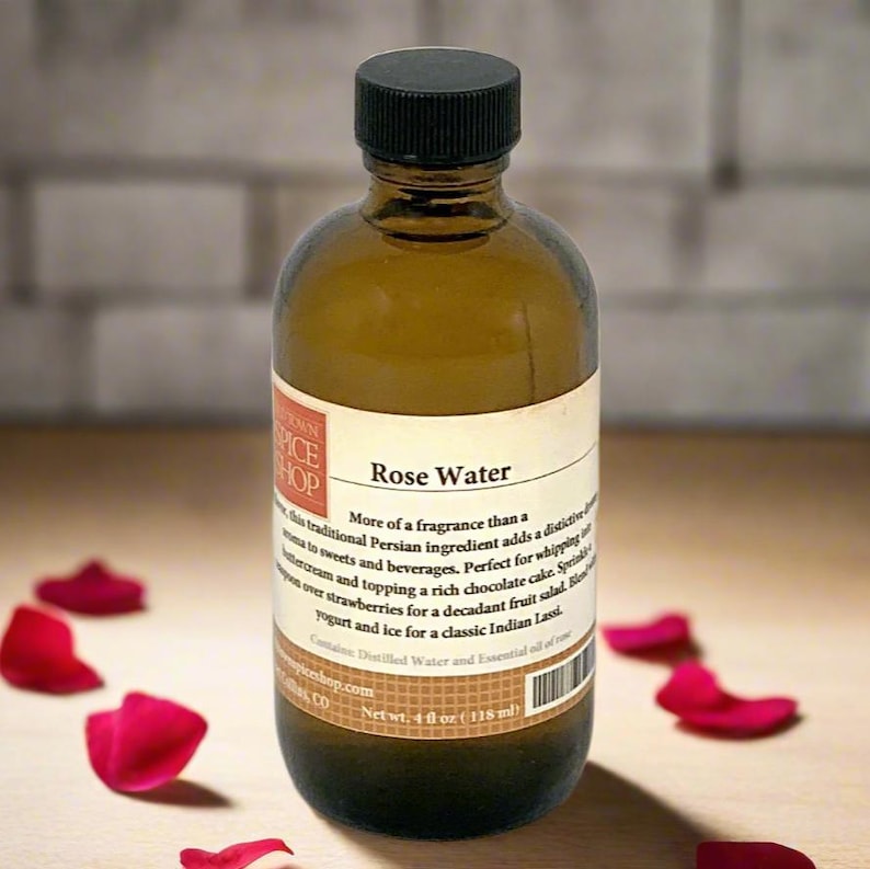 K&ouml;nnte beinhalten: Eine braune Glasflasche mit Rosenwasser, schwarzem Deckel und wei&szlig;em Etikett. Das Etikett hat Text und ist von roten Rosenbl&auml;ttern umgeben. Die Flasche enth&auml;lt 118 ml Rosenwasser.