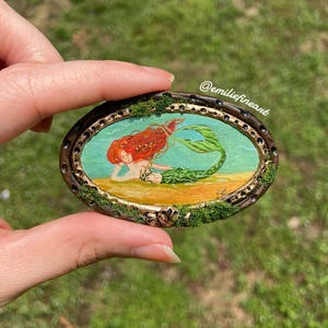 Miniatura original de sirena con pintura ovalada cubierta de musgo verde a escala 1:12.