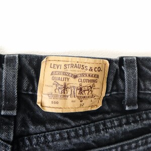 May include: Black denim jeans featuring a tan leather-like patch on the back waistband. The patch displays the text Levi Strauss & Co. Original Riveted Quality Clothing, two horses pulling a pair of jeans, the number 550, and the size W 32.