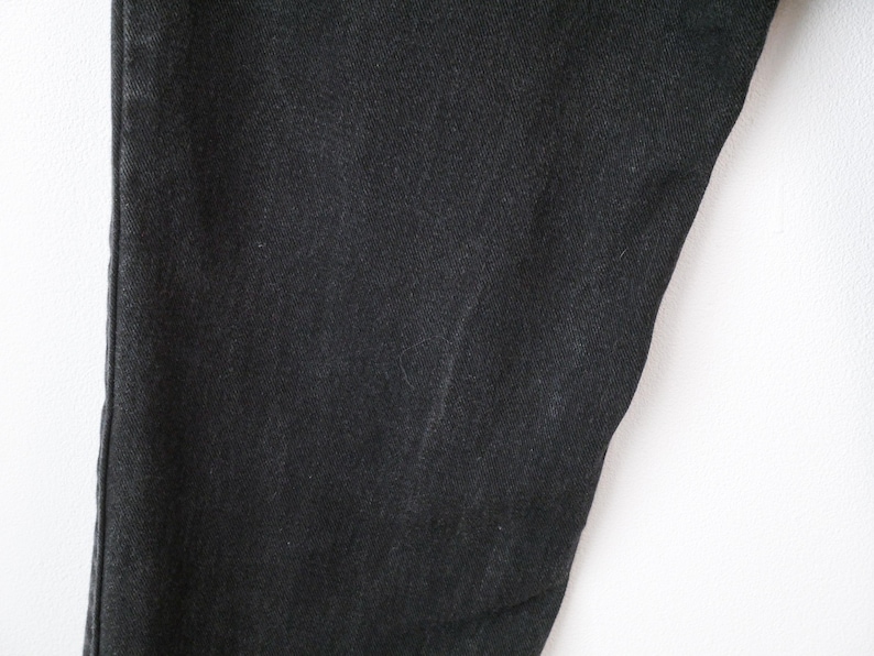 Op de afbeelding: Een zwarte spijkerbroek van denim met een klassieke rechte snit en zichtbare verticale stiksels langs de zijnaad. De stof vertoont een consistente donkergrijze wassing met een subtiele textuur die kenmerkend is voor geweven katoenen denim.