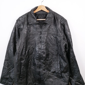 May include: Black leather jacket with a patchwork design, hanging on a wooden hanger. The jacket has a full zip closure, a collar, and two front pockets. The jacket is displayed against a white background.