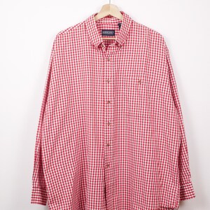 May include: A red and white gingham button-down shirt hanging on a wooden hanger. The shirt has long sleeves, a button-down collar, and a chest pocket. The brand name "LANDS' END" is visible on the collar.