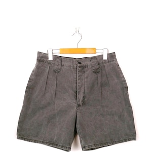 以下が含まれることがあります： 木製のハンガーに掛けられたグレーのハイウエストショーツ。 ショーツはボタン留め、プリーツ、ポケット付きです。 生地は色あせた質感です。 ショーツはニュートラルカラーで、さまざまな服装に合わせやすいです。