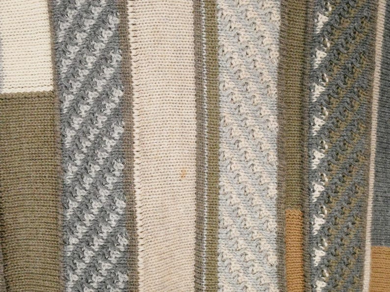 Puede incluir: Primer plano de un textil de punto con rayas verticales en varios colores y texturas. El dise&ntilde;o incluye secciones en crema, gris, verde oliva y beige. Algunas rayas tienen un punto texturizado y estampado.