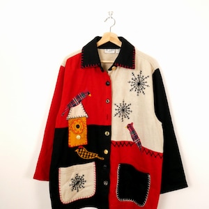 May include: A patchwork jacket in red, black, and cream, decorated with appliqued birds, birdhouses, and snowflakes. The jacket has a black collar and cuffs, and is fastened with buttons. The winter-themed design is whimsical and eye-catching.