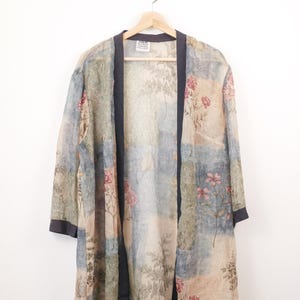 Può includere: Una vestaglia leggera in stile kimono aperta sul davanti con un design patchwork di quadrati nei toni del blu, verde e beige spenti. Il tessuto è decorato con una delicata stampa floreale nei toni del rosa e del verde. Presenta un bordo grigio scuro e un'etichetta con la scritta R&M RICHARDS.