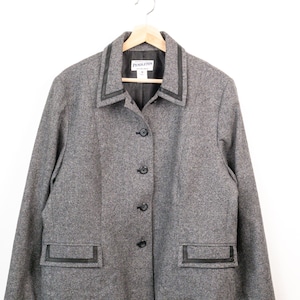 May include: A grey wool-blend jacket featuring a pointed collar with black leather trim, a four-button front closure, and two front flap pockets accented with black leather piping. The interior label reads Pendleton, and the jacket is fully lined.