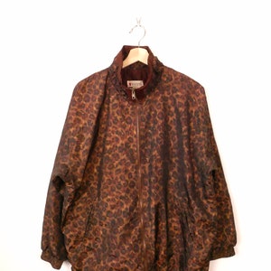 May include: A brown and gold leopard print jacket with a zip closure and the word "AVON" on the front.