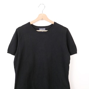 May include: A black short-sleeved sweater on a wooden hanger. The sweater features a crew neck and a small label at the neckline. The Lands' End label is visible. The background is plain white.