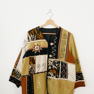 May include: A patchwork jacket with a V-neck and long sleeves. The jacket features a mix of patterns, including animal print, geometric shapes, and swirls, in shades of brown, tan, black, and white. It has three decorative buttons.