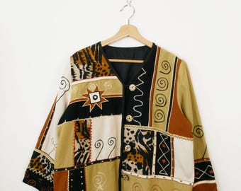 Może przedstawiać: Kurtka patchwork z dekoltem w serek i długimi rękawami. Kurtka posiada mieszankę wzorów, w tym zwierzęcy nadruk, kształty geometryczne i wiry, w odcieniach brązu, beżu, czerni i bieli. Posiada trzy ozdobne guziki.