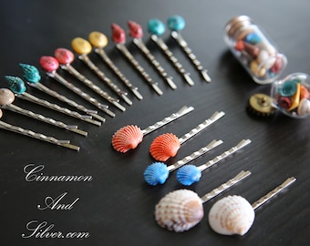 May include: A set of silver hair clips with various colored shell and bead embellishments. The clips are arranged on a dark surface. The image also shows a small glass jar filled with similar embellishments.