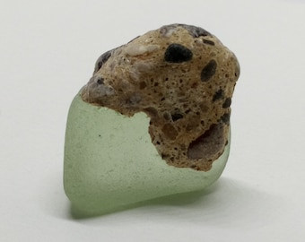 Pezzo di vetro marino incastonato in pietra - insoliti reperti sulla spiaggia