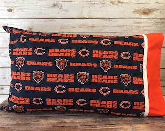 May include: A navy blue pillowcase with a white and orange border. The pillowcase features a repeating pattern of the Chicago Bears logo, which includes the team's name and a bear head.