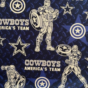 Op de afbeelding: Blauwe stof met een herhalend patroon van witte sterren, Captain America en de woorden "Cowboys America's Team".