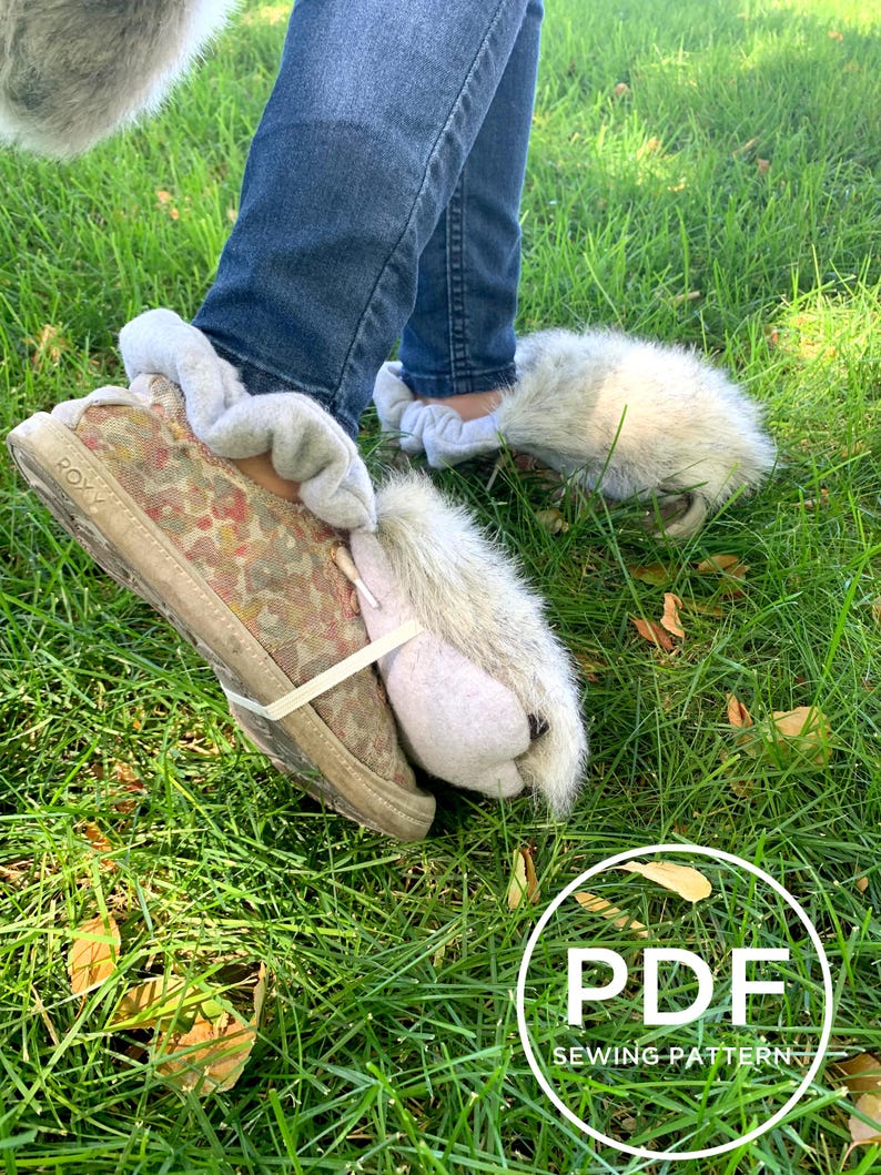 May include: A pair of fluffy grey slipper boots with a white cuff and a camouflage print on the sole. The boots are being worn by a person wearing blue jeans. The image includes the text "PDF SEWING PATTERN".