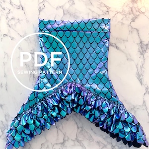 May include: A mermaid tail sewing pattern in PDF format. The tail is made of iridescent blue and purple fabric with a scale pattern. The tail has a ruffle trim around the bottom.