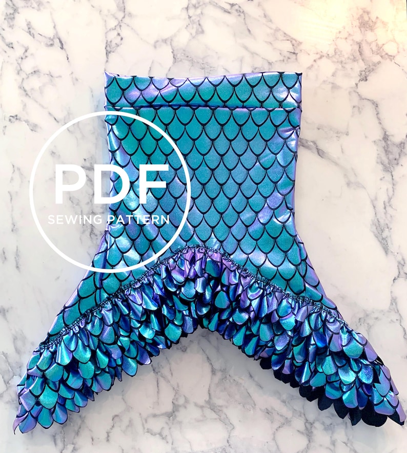 May include: A mermaid tail sewing pattern in PDF format. The tail is made of iridescent blue and purple fabric with a scale pattern. The tail has a ruffle trim around the bottom.