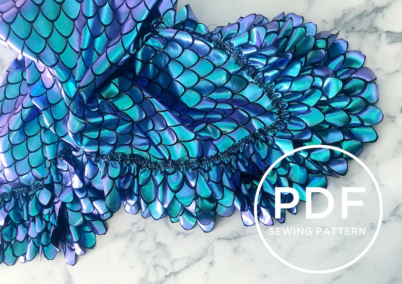May include: A blue and purple iridescent fabric with a scale pattern and a ruffled edge. The fabric is folded and the text "PDF SEWING PATTERN" is visible in a circle.