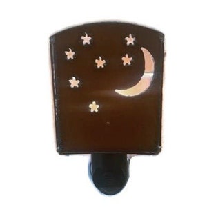 May include: A brown night light with a crescent moon and star cutouts. The night light has a rectangular shape with a rounded top and a black base. The moon and stars are illuminated when the light is on.