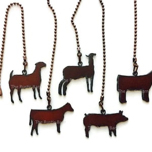 May include: Five different metal fan pull chains with animal silhouettes. The animals are a pig, a cow, a goat, a llama, and a sheep. The chains are copper colored and have a rustic finish. The text "The Rustic Barn" is on each of the animal silhouettes.