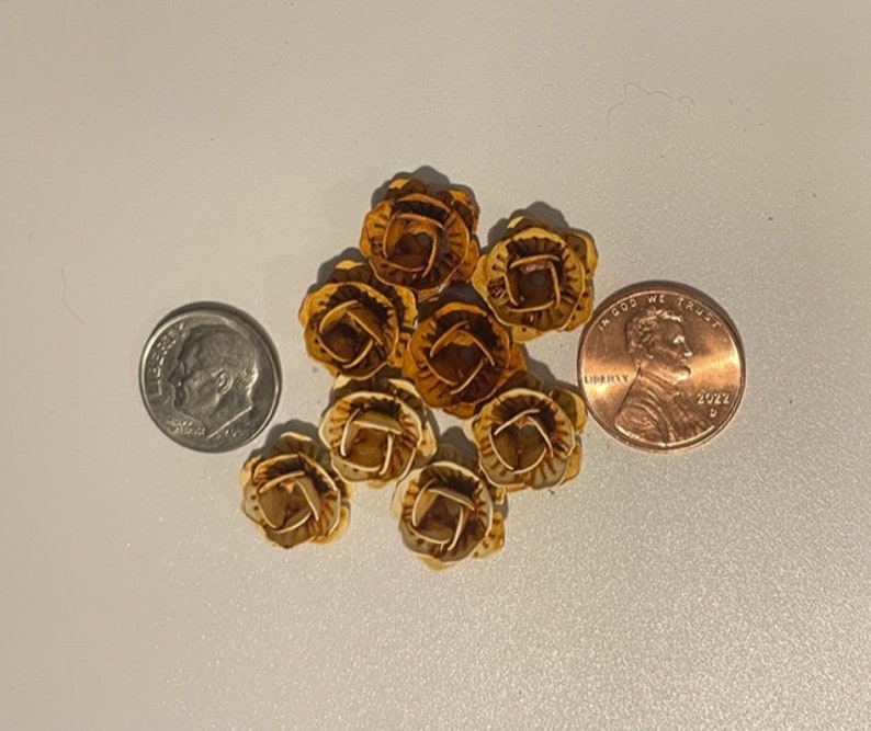 May include: A group of eight small, decorative, gold-colored buttons with a floral design. The buttons are about the size of a US penny.
