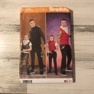 Puede incluir: Patrón de costura Simplicity S8975 A, con diseños de disfraces. El patrón incluye varios atuendos, con opciones para adultos y niños. La portada muestra imágenes de las prendas terminadas, mostrando diferentes estilos y tallas.