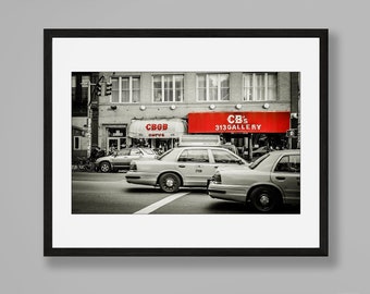 May include: Black and white photograph of a city street scene with three yellow taxis driving past a red storefront with the text "CB's 313 GALLERY" on it.