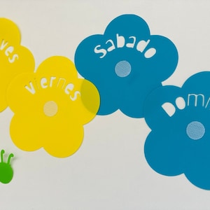 May include: A colorful flower-shaped calendar with the days of the week in Spanish: Jueves, Viernes, Sabado, Domingo. The flowers are yellow and blue.