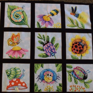 May include: Fabric panel featuring a repeating pattern of whimsical insects and flowers. Each square showcases a different bug, including ladybugs, bees, and butterflies, alongside sunflowers and other blooms. The design is set against a light blue background.