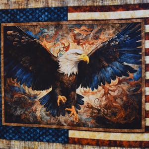 May include: A patriotic quilt featuring a majestic bald eagle with outstretched wings. The eagle is depicted with detailed feathers and a piercing gaze, set against a backdrop of swirling colors. The quilt's border incorporates the American flag's stars and stripes.