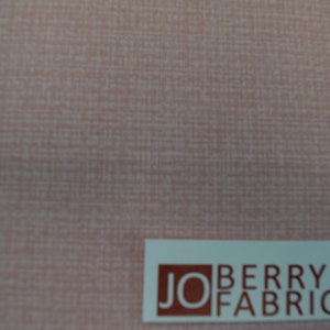 May include: A close-up of a pale pink fabric with a subtle woven texture. The fabric is labeled "JO BERRY FABRICS" in brown text on a white label.