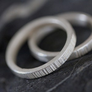May include: Two silver rings with a textured finish. The rings are stacked on top of each other.