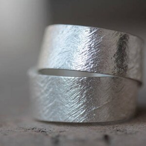 May include: Two silver rings with a textured, hammered finish. The rings are stacked on top of each other.