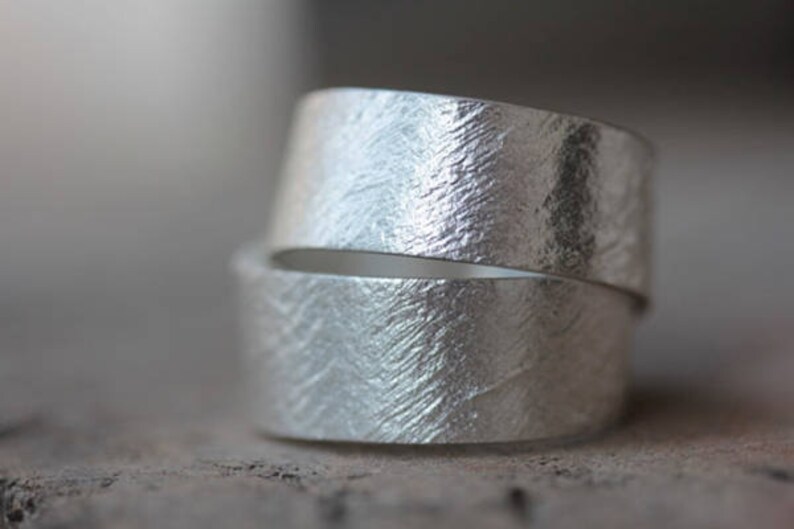 May include: Two silver rings with a textured, hammered finish. The rings are stacked on top of each other.