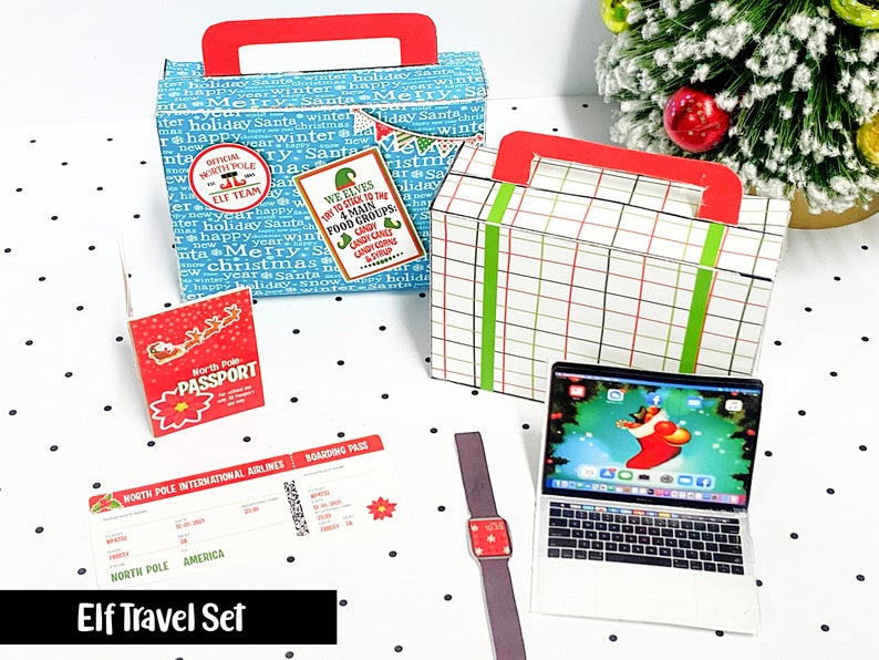 May include: A miniature Elf Travel Set featuring two suitcases, a passport, a boarding pass, a smartwatch, and a laptop. The suitcases have red handles and are decorated with holiday-themed patterns and stickers. The laptop displays a Christmas scene.