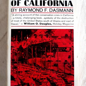 Puede incluir: Un libro de bolsillo titulado The Destruction of California de Raymond F. Dasmann. La portada blanca presenta texto negro y una fotografía en tonos rojos de una autopista congestionada con coches, incluyendo señales de Figueroa St US 6-99 y Pasadena US 66.
