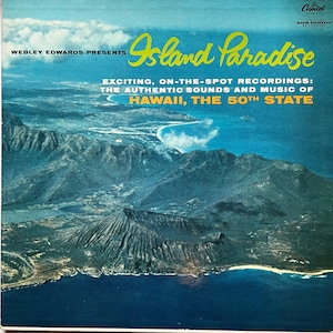 May include: An aerial view of a volcanic island with a blue ocean and a sandy beach. The text "Island Paradise" is written in yellow cursive letters on the top of the image. The text "Exciting, on-the-spot recordings: The authentic sounds and music of Hawaii, the 50th state" is written in black letters below the title.
