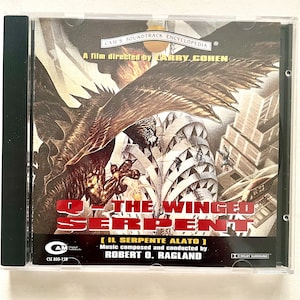 Peut inclure: Une pochette de CD représentant un serpent ailé noir et brun attaquant une ville. Le texte sur la pochette indique "Q - The Winged Serpent (Il Serpente Alato)" et "Musique composée et dirigée par Robert O. Ragland".