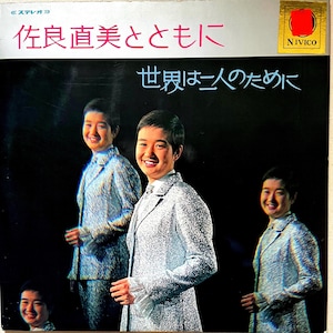 May include: Vintage vinyl record album cover featuring a smiling person in a silver suit. The album title is in Japanese, with additional Japanese text below. The background is black, and the album cover has a gold and red sticker in the upper right corner.