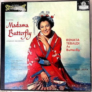 May include: Vintage vinyl record album cover for Puccini's "Madama Butterfly" featuring Renata Tebaldi. The cover displays a woman in a red kimono with floral patterns, holding a fan. The album title and artist names are prominently displayed.