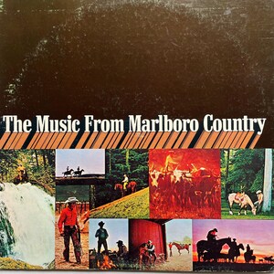 May include: A vintage vinyl record album cover with a brown background and the text "The Music From Marlboro Country". The cover features a collage of images of cowboys on horseback, cattle, and a waterfall.