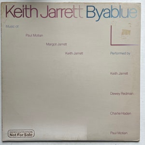 Może przedstawiać: Biała okładka winylowego albumu z tytułem "Keith Jarrett Byablue" w czerwonych i niebieskich literach. Album zawiera muzykę Paula Motiana, Margot Jarrett i Keitha Jarretta. Wykonali go Keith Jarrett, Dewey Redman, Charlie Haden i Paul Motian. Na dole okładki znajduje się czarna pieczątka z napisem "Demonstration Not For Sale."