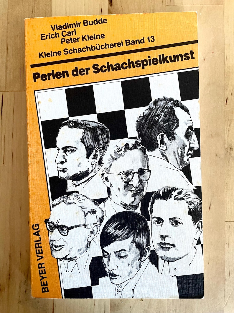 May include: A yellow book with black text titled "Perlen der Schachspielkunst" by Vladimir Budde, Erich Carl, and Peter Kleine. The book is part of a series called "Kleine Schachb&uuml;cherei Band 13". The cover features a black and white chessboard with illustrations of six people.