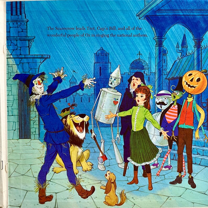 May include: Illustration from a children's book depicting characters from The Wizard of Oz. The Scarecrow, Tin Man, Lion, and others are singing. The text reads, "The Scarecrow leads Trot, Cap'n Bill, and all of the wonderful people of Oz in singing the national anthem."