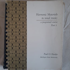 Op de afbeelding: De omslag van een boek getiteld "Harmonic Materials in tonal music: a programed course Part I" door Paul O. Harder, Michigan State University. De omslag is wit met zwarte tekst en een gouden achtergrond met een herhalend patroon van zwarte cirkels.