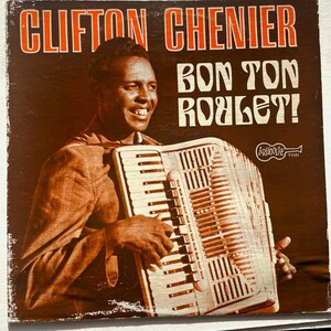 May include: A vintage record album cover featuring Clifton Chenier, a renowned zydeco musician, playing an accordion. The album title is "Bon Ton Roulet!" and the record label is "Arhoolie" with the number "1031".