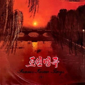 Op de afbeelding: Een vierkante vinylhoes met een zonsondergang boven een rivier, een brug en treurwilgen in dieprode en oranje tinten. De tekst "조선명곡", "Famous Korean Songs" en "(1)" staat in witte en zwarte letters op de afbeelding weergegeven.