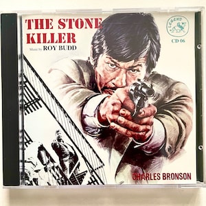 May include: A CD cover featuring a man holding a gun, with the text "THE STONE KILLER" and "CHARLES BRONSON" in red. The text "Music by ROY BUDD" is also present.